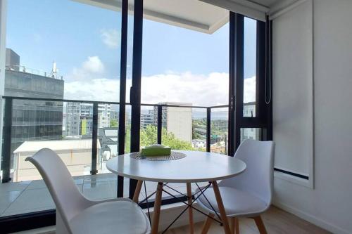 a table and chairs in a room with a large window at Sky Stars CBD Apartment in Auckland