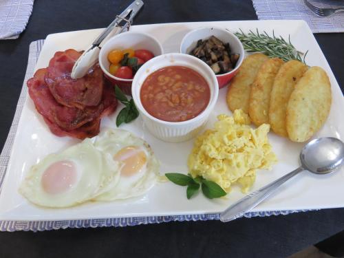 a plate of breakfast food with eggs sausage and beans at Birdsong Alley Bed and Breakfast in Hanmer Springs