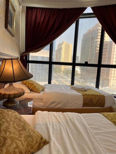 two beds in a hotel room with a large window at فندق لابا دارنا in Makkah