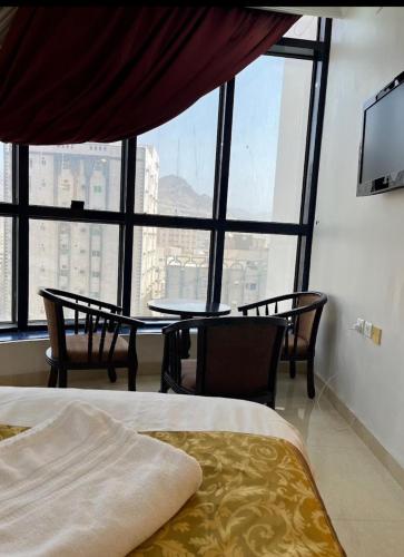 a bedroom with a table and chairs and a large window at فندق لابا دارنا in Makkah