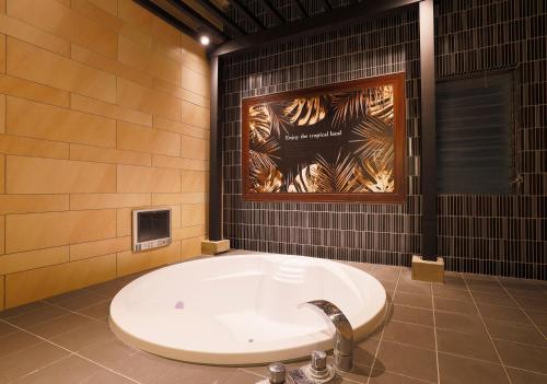 ホテルウォーターゲート香芝 في Kashiba: حوض استحمام في الحمام مع ملصق على الحائط
