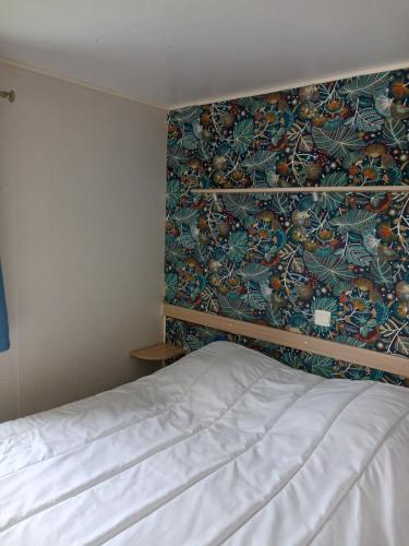 - une chambre avec un lit orné d'un mur fleuri dans l'établissement Mobil home L42, à Le Portel