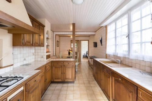 a large kitchen with wooden cabinets and a large window at Maison avec jardin proche gare plage intramuros chien admis Fibre in Saint Malo