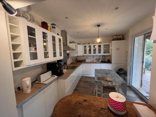 a large kitchen with white cabinets and a table at Chalet d’Ax Pyrénées in Ax-les-Thermes