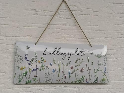 a sign with flowers on it hanging on a wall at Kleine Auszeit in Cochem