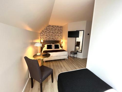 a bedroom with a bed and a table and a chair at Logis - Hôtel de la Baie de Somme in Le Crotoy