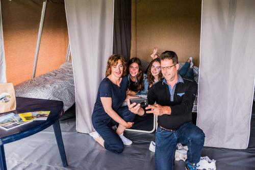 un grupo de personas sentadas en una habitación con una tablet en Country Camp Camping Gritt en Diekirch