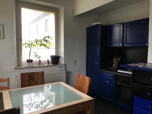 cocina con armarios azules, mesa y ventana en Pension Deinhardt en Hirschaid