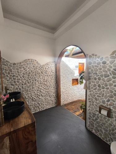 a bathroom with a stone wall with a sink at U Story Resort in Siquijor