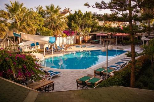 西代的住宿－Akalia Suite Hotel & SPA，一个带桌椅的游泳池,棕榈树