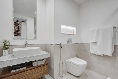 a white bathroom with a sink and a toilet at Trophy Twinkle Twine Jumeriah Retreat Suites in Dubai