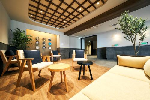 a lobby with couches and chairs and a table at Rakuten STAY Kokura Station in Kitakyushu