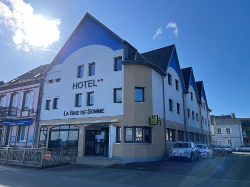 a large white hotel with a car parked in a parking lot at Logis - Hôtel de la Baie de Somme in Le Crotoy