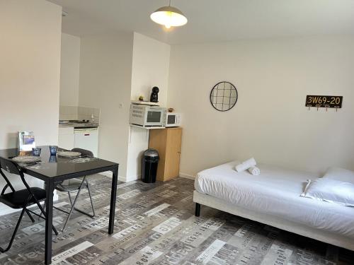 - une chambre avec un lit, une table et un four micro-ondes dans l'établissement Le Vinci 3, à Calais
