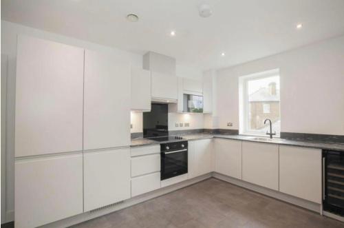 a white kitchen with white cabinets and a window at 2 Bedroom Apartment In Kew Bridge in Kew Bridge