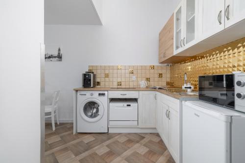 a kitchen with a washing machine and a washer at Studio Apartment with Mezzanine near Kraków City Centre by Renters in Krakow