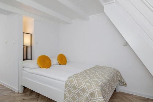 a white bedroom with a bed with yellow pillows at Studio Apartment with Mezzanine near Kraków City Centre by Renters in Krakow