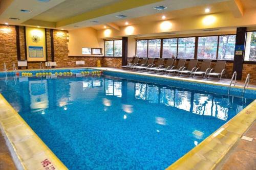 a large swimming pool with chairs in a building at 2BD App in Bojurland FREE Pool SPA Parking and Skishuttle in Bansko