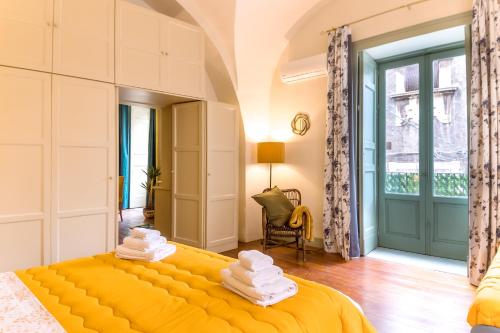 een slaapkamer met een geel bed en handdoeken bij Sikelia Luxury home in Catania