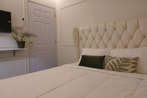 a bedroom with a large white bed with a large headboard at AboutTime Bangkok in Bangkok