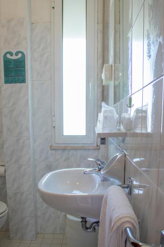 a white bathroom with a sink and a toilet at Hotel Apollonia in Lido di Savio