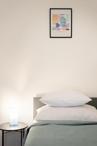 a white bedroom with a bed and a picture on the wall at Prague - Karlin Apartments in Prague