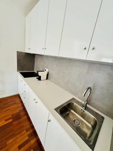 a kitchen with white cabinets and a stainless steel sink at Altamira Studio in Viana do Castelo