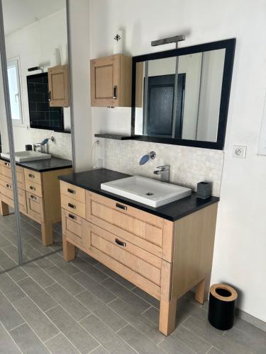 une salle de bain avec un lavabo et un miroir dans l'établissement Maison spacieuse, à Marennes