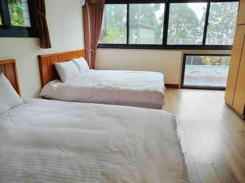 a bedroom with two beds and a large window at Gemlu in Lugu