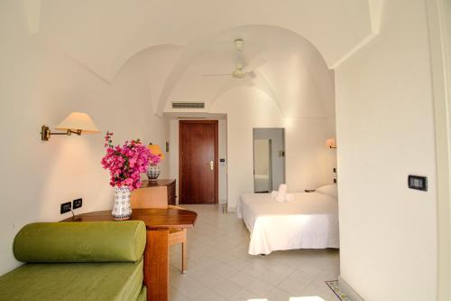 - une chambre avec un lit et un vase de fleurs sur une table dans l'établissement Mursia Wellness Hotel, à Pantelleria