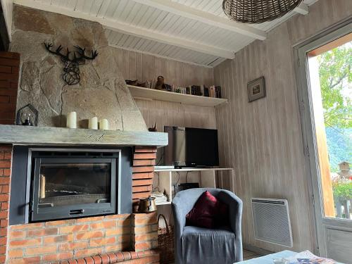 a living room with a fireplace and a chair at Le Chalet de Larcat in Larcat
