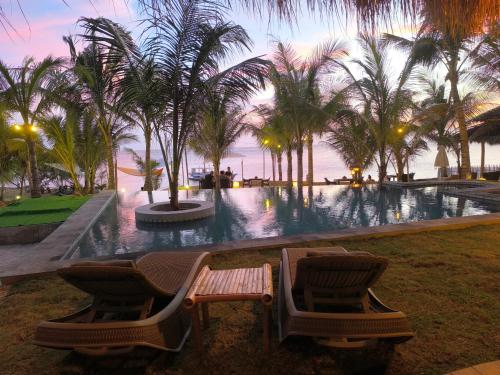 a resort pool with two chairs and palm trees at U Story Resort in Siquijor
