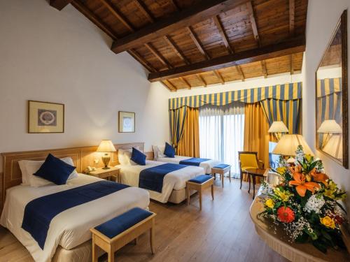 Habitación de hotel con 2 camas, sillas y flores en Hotel Orologio, en Ferrara