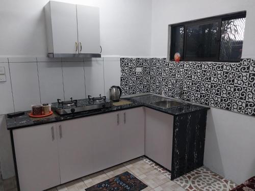 una cucina con armadi bianchi e piano di lavoro nero di Chands Homestay Apartment a Lautoka