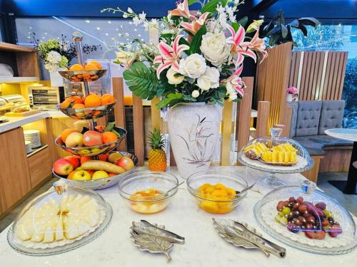 uma mesa com pratos de frutas e um vaso de flores em Hotel Bolzano em Milão