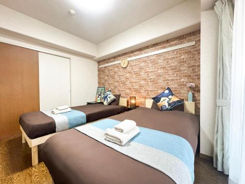 two beds in a room with a brick wall at nestay apartment tokyo akihabara in Tokyo