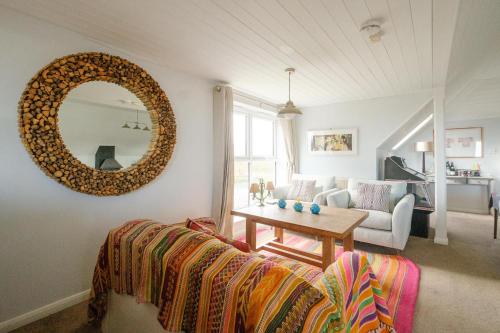 Una sala de estar con un sofá y un espejo. en Fishermans Loft - A seaside house in Thorpeness with direct access to the beach - Aldeburgh Coastal Cottages, en Thorpeness