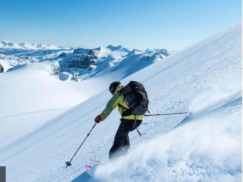 a man is skiing down a snow covered slope at Strøken villa med spektakulær utsikt in Tromsø