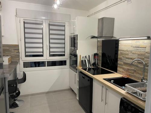 une cuisine blanche avec un évier et une fenêtre dans l'établissement Super appartement By live cité gastronomique, à Dijon