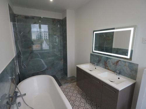 La salle de bains est pourvue d'une baignoire, d'un lavabo et d'une douche. dans l'établissement Maison 3 chambres tout confort !, à Seclin