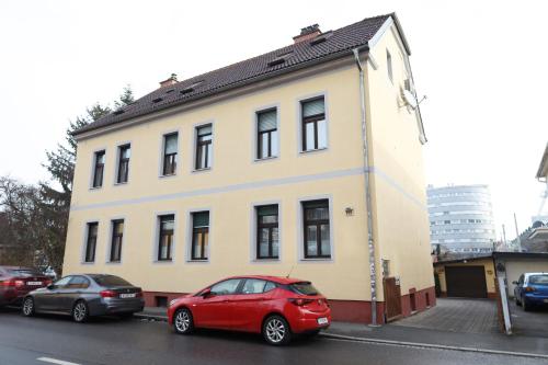 ein rotes Auto, das vor einem Gebäude parkt in der Unterkunft Arena Apartments in Graz