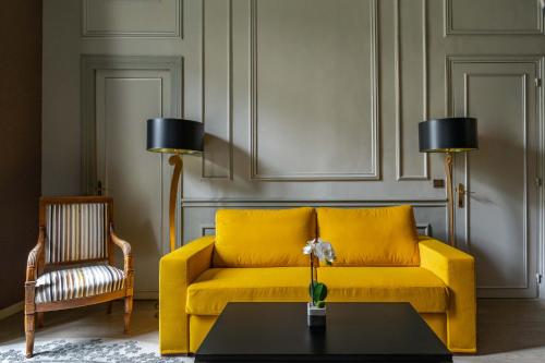 a yellow couch in a living room with a table at Hôtel Regent's Garden - Astotel in Paris