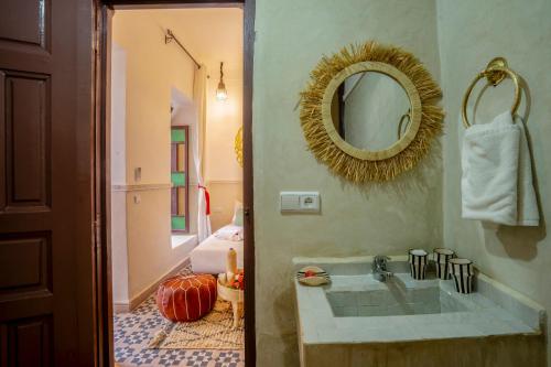 Riad Nuits D'orient Boutique Hotel & SPA في مراكش: حمام مع حوض ومرآة على الحائط
