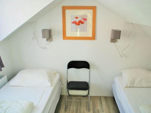 Habitación con 2 camas y una silla. en Vakantiehuis Voor Anker, en Egmond aan Zee