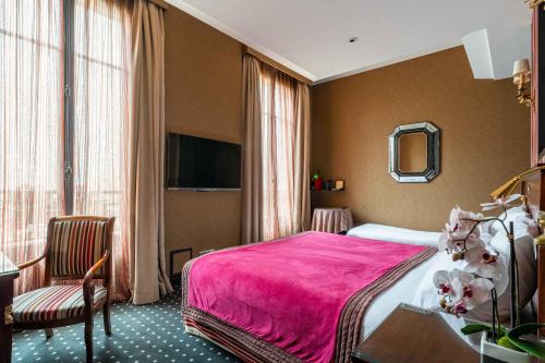 a hotel room with a pink bed and a chair at Hôtel Regent's Garden - Astotel in Paris