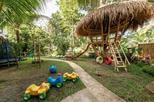 ein Spielplatz mit vielen Spielzeugen im Gras in der Unterkunft 2BR Haven with Pool & Lush Garden - Embrace Bali's Soul Near Temples, Beaches & Rice Fields in Ubud