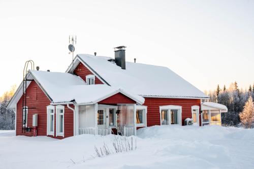 une maison rouge avec de la neige sur le toit dans l'établissement Hommala, à Raiskio