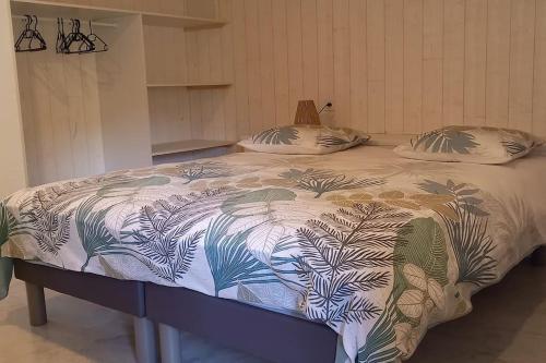 ein Bett mit einer Bettdecke mit Pflanzen drauf in der Unterkunft Une pause Champêtre : gîte avec terrasse in Saint-Cierge-sous-le-Cheylard