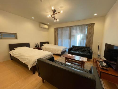 a bedroom with two beds and a couch and a tv at SALON Shibuya in Tokyo