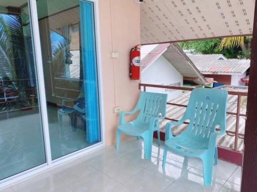 zwei blaue Stühle auf der Veranda eines Hauses in der Unterkunft Baan chidlomlay in Don Sak